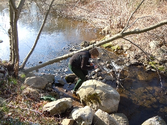 A volunteer monitor checks the water temperature on the Millers River in Cumberland, RI